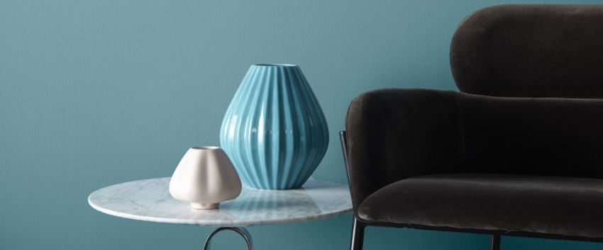 A tranquil blue wall with a gray chair and vases