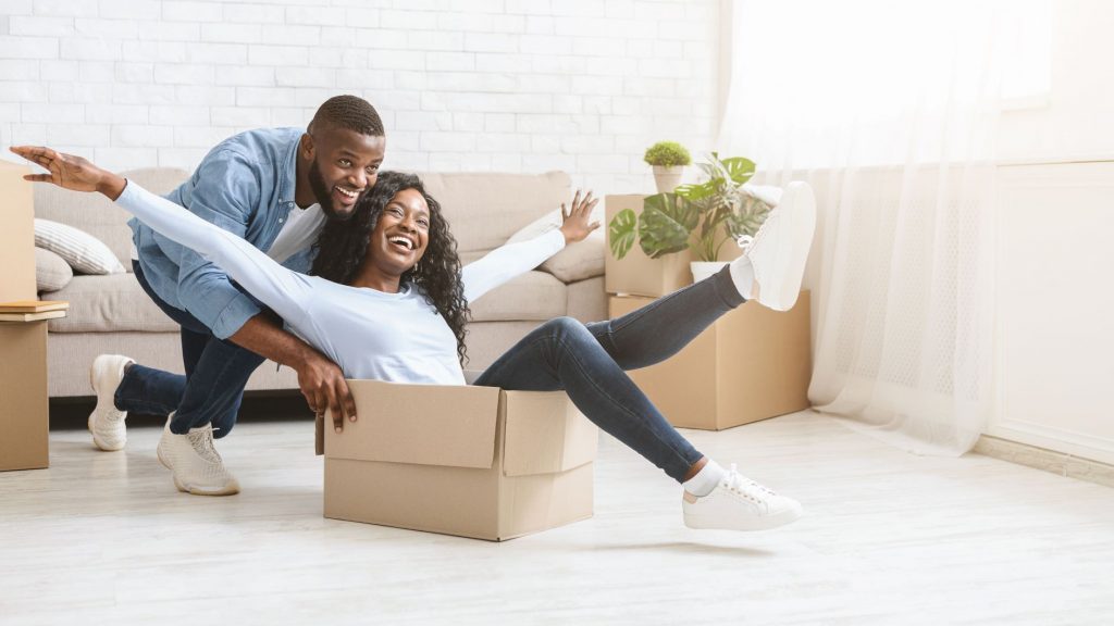 Man pushing happy woman in moving box