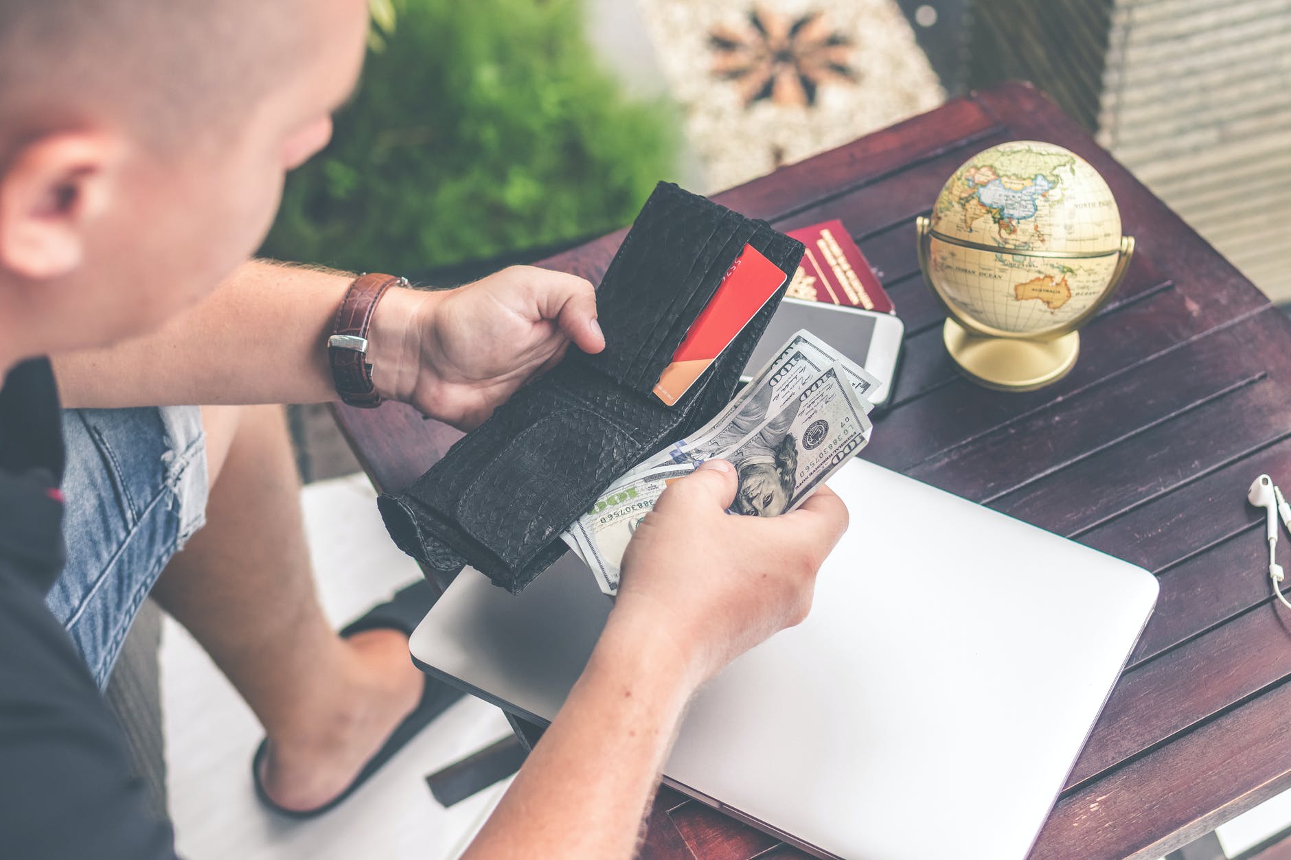 man holding u s dollar banknotes and black leather bi fold wallet