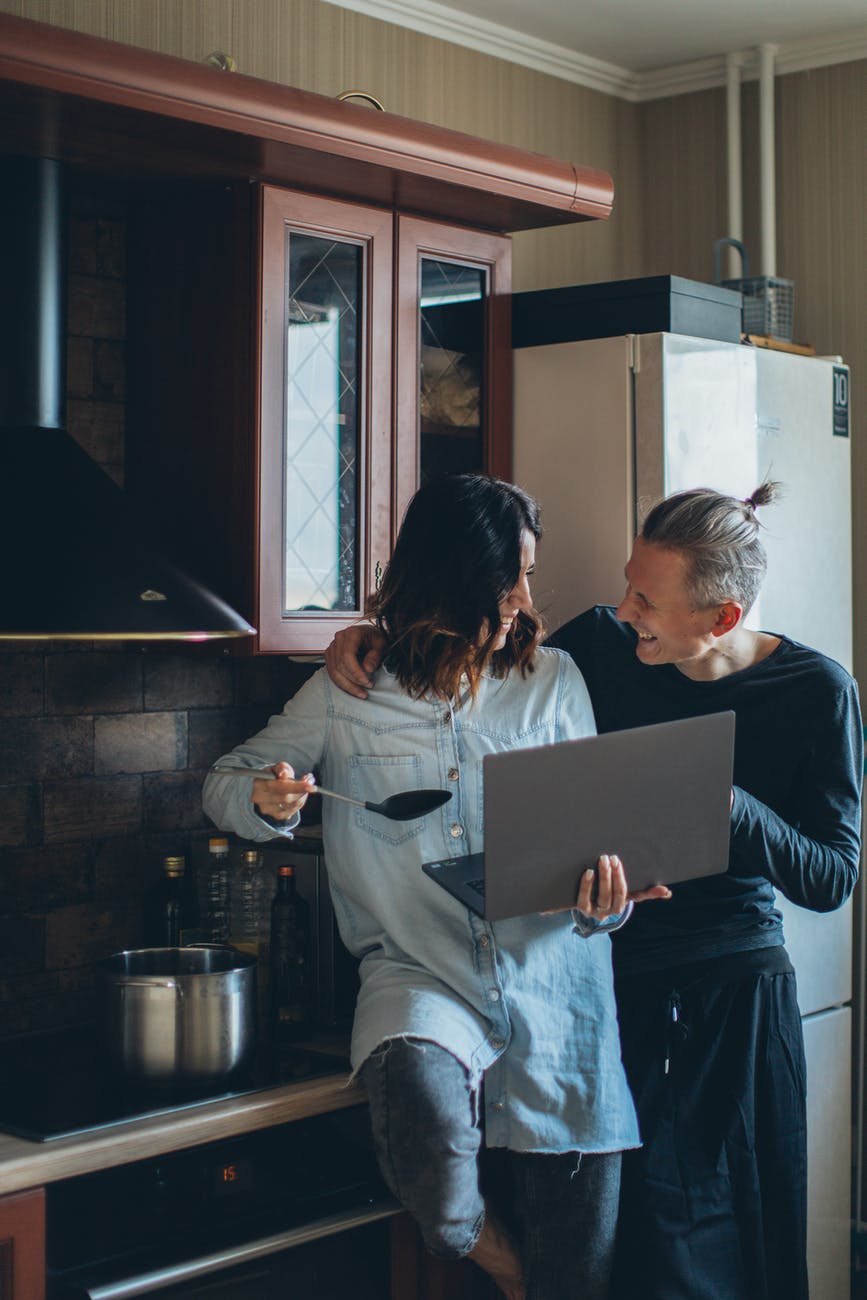 woman cooking while holding her laptop